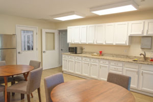 Communal dining room with fridge, microwave, sink, cabinets and seating