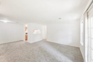 Interior unit Living Room, white walls, wood like floors in kitchen, neutral toned carpeting.