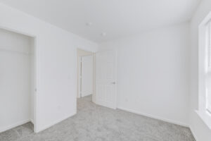 Interior Unit Bedroom, White walls, neutral toned carpeting.