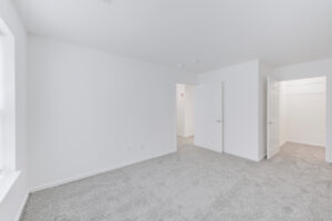 Interior Unit Bedroom, white walls, neutral toned carpeting, walk in closet, window on right wall when entering bedroom.